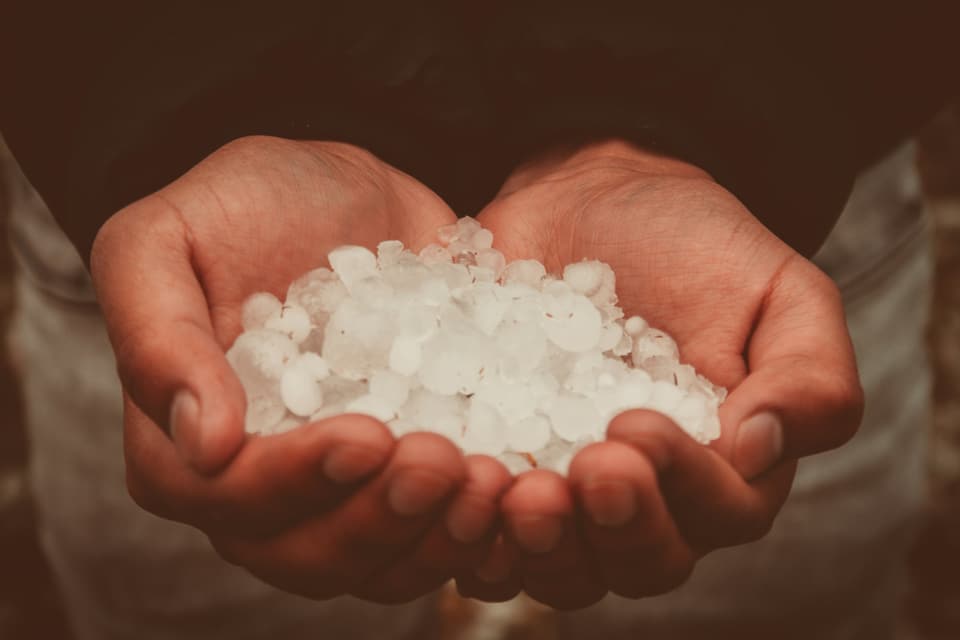 A pair of cupped hands holding a pile of hailstones