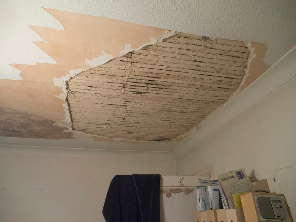 A plaster ceiling that has fallen away, exposing the wooden lath above